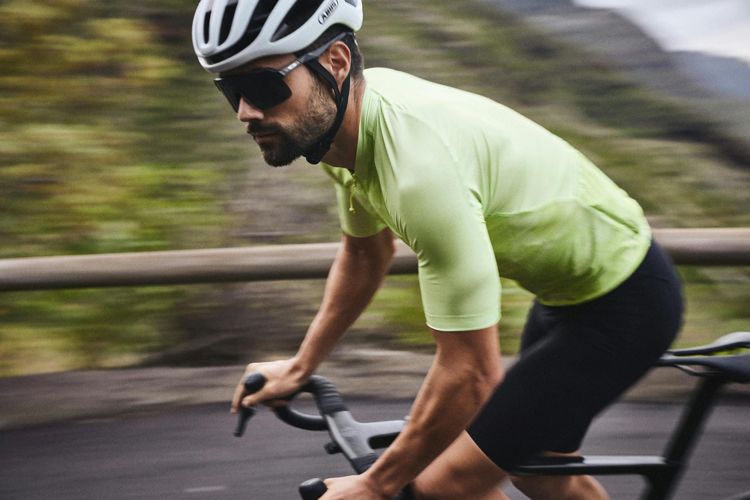 Man in green jersey and white helmet riding his road bike quickly