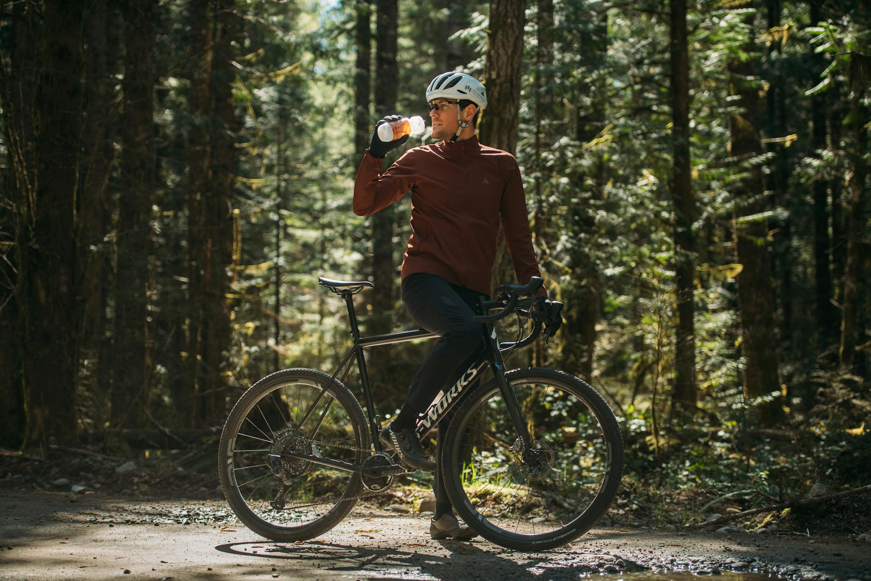 Man drinking water on a bike in the forest.