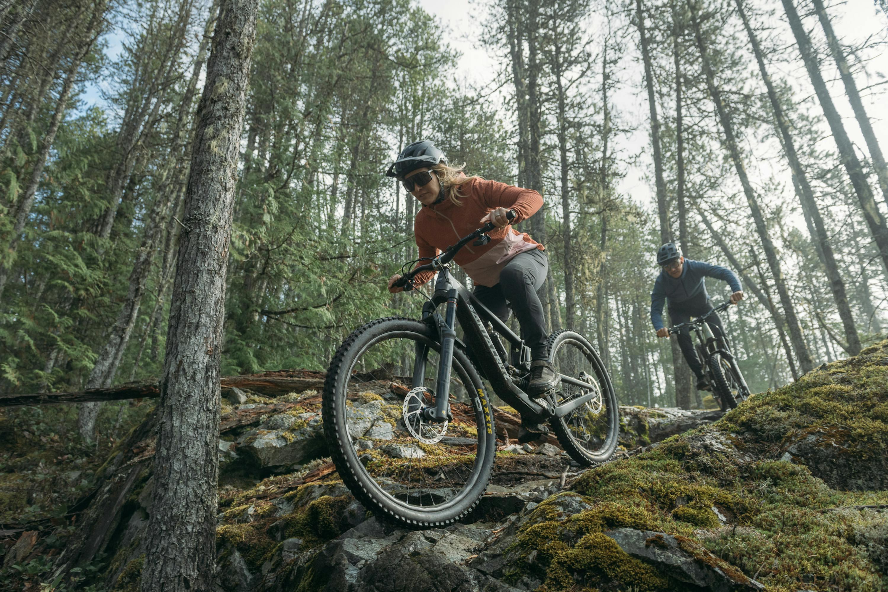 Woman and man riding a bike in the forest.