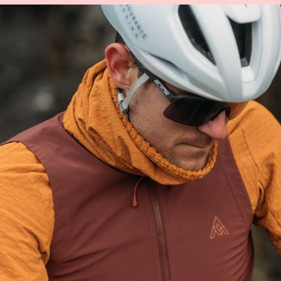 Man wearing a bike helmet looking down wearing a neck gaiter