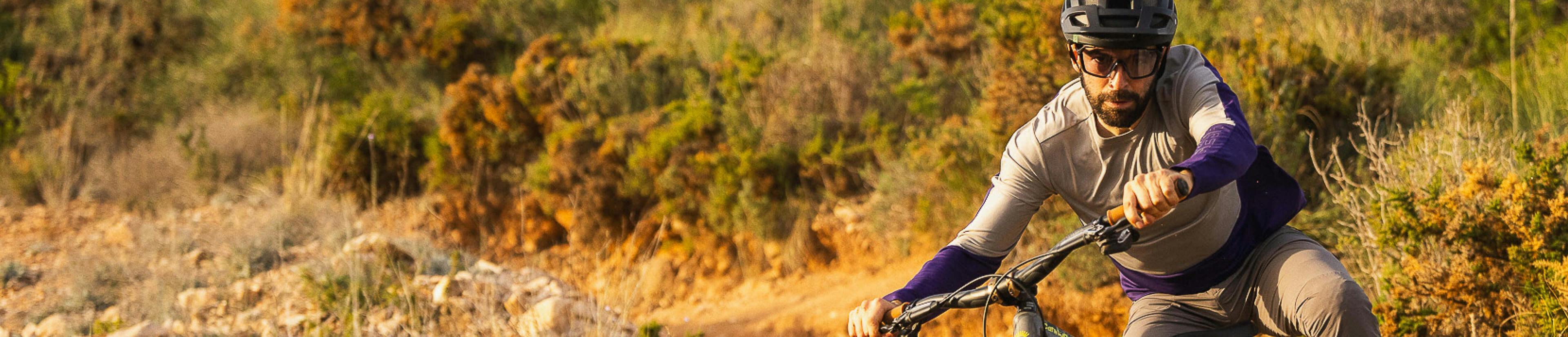 Man wearing a purple and grey shirt riding a bike