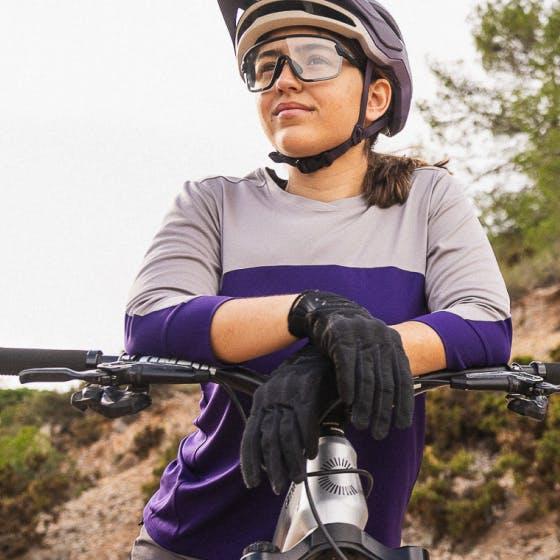 Woman wearing a purple and grey shirt sitting on a bike