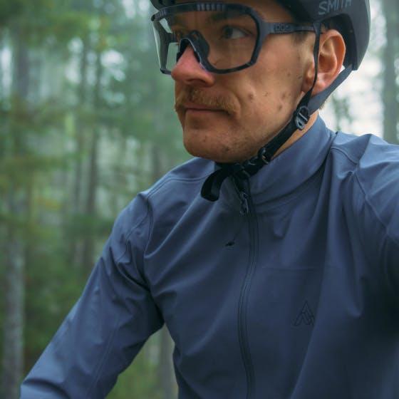 Man wearing a blue jacket and a bike helmet looking out into the world. 